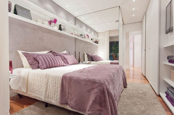 Quarto lilás com parede de espelho e roupa de cama lavanda