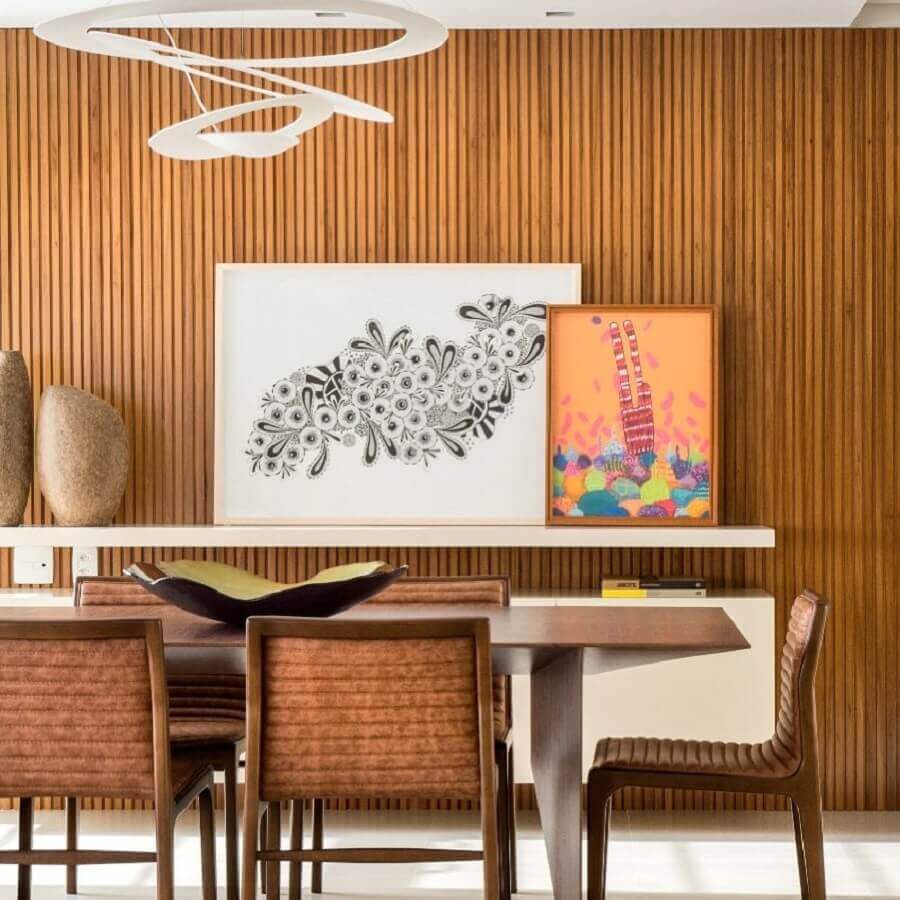 Ripado de madeira na parede de sala de jantar decorada com quadros apoiados em prateleira Foto Paula Neder Arquitetura