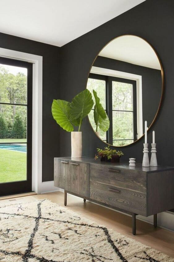 Sala com parede preta e espelho redondo