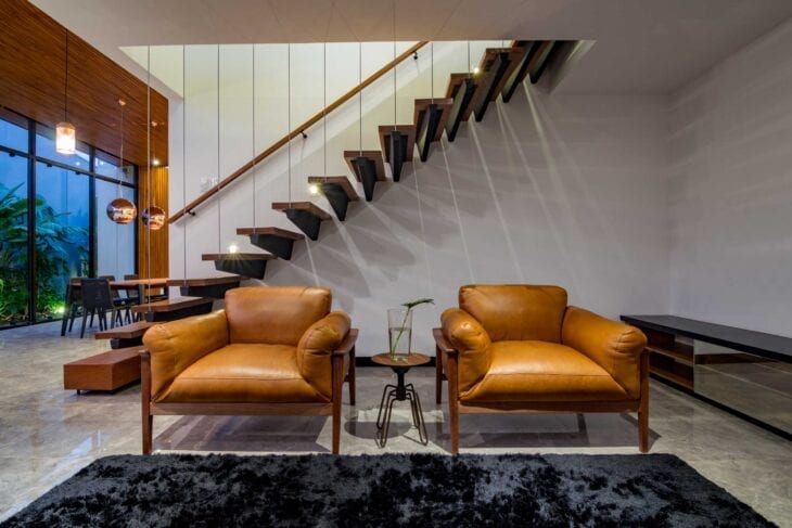 Sala com poltronas de couro e escadas modernas