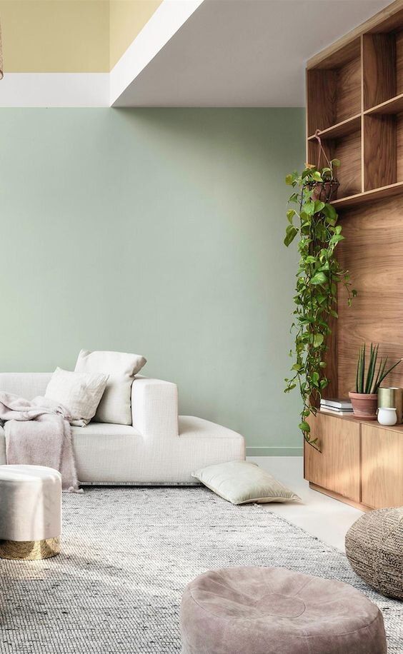 Sala de estar moderna com parede verde pastel e sofá branco