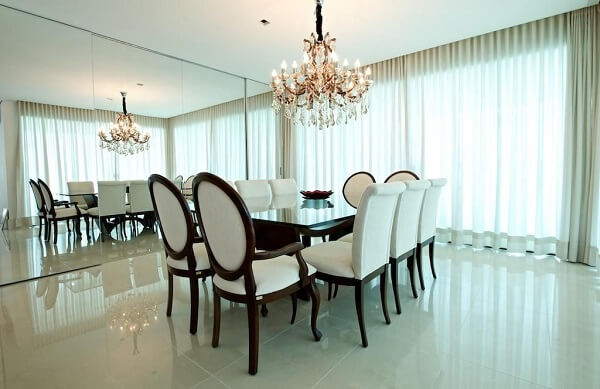 Sala de jantar preta e branca com parede espelhada e cortina bege
