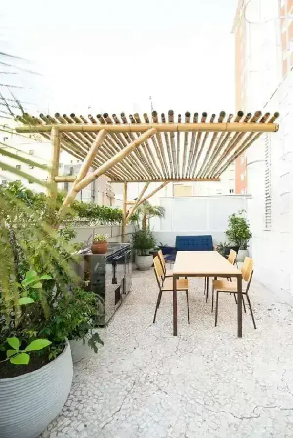 Terraço com pergolado de bambu e mesa de madeira
