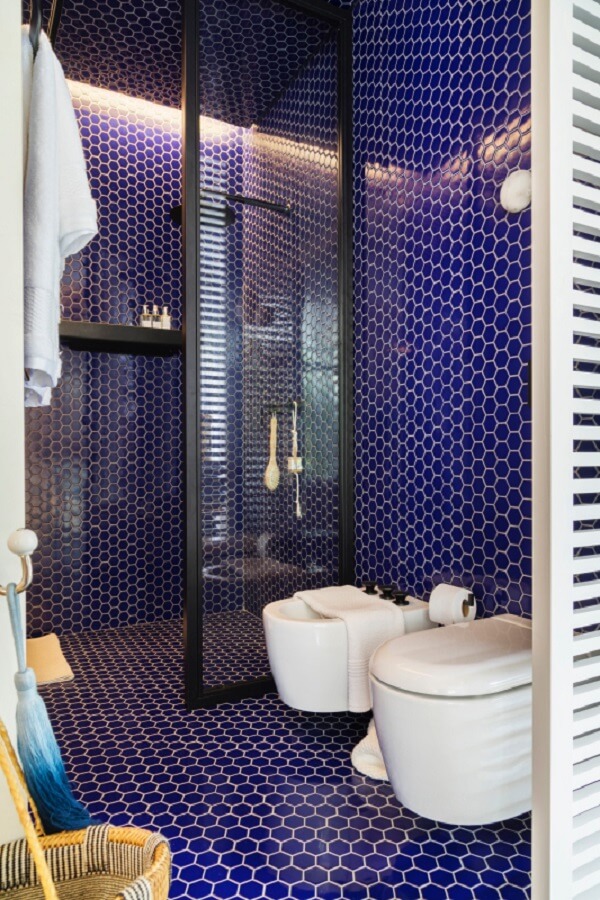 Banheiro moderno azul com chuveiro preto e vaso sanitário branco