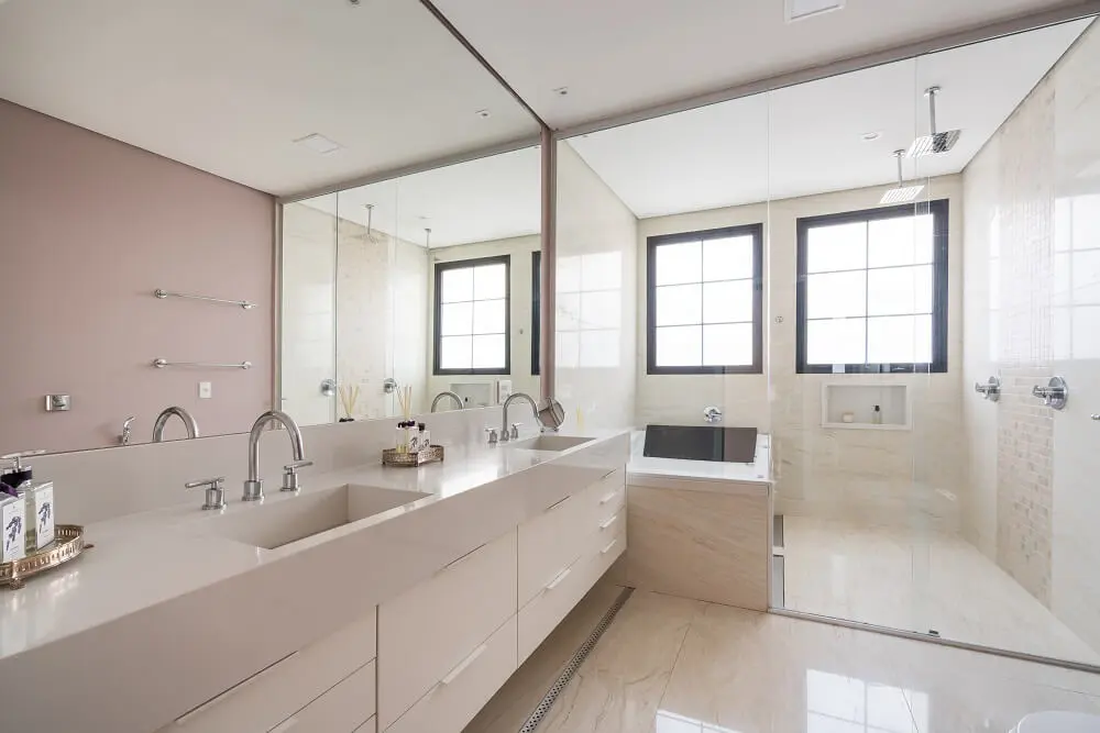 Banheiro do casal clean com bancada suspensa, banheira e área de box. Foto: Kadu Lopes