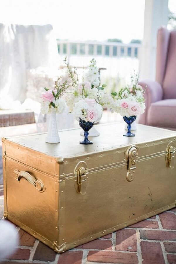 Baú de madeira pintado na cor dourada para sala de estar decorada em rosa e azul