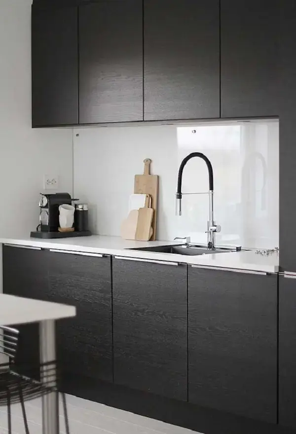 Decoração com armário de cozinha com pia planejado na cor preta e bancada branca