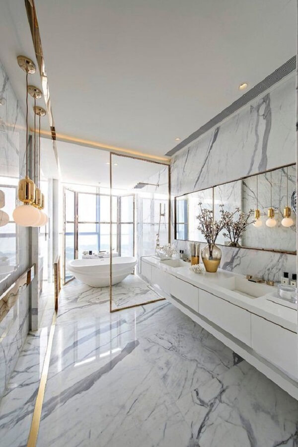 Revestimento marmorizado no banheiro amplo com detalhes na cor dourada