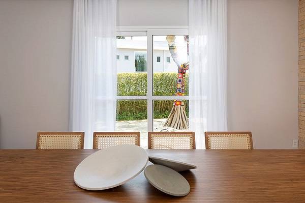 Sala de jantar com cortina branca na porta de vidro