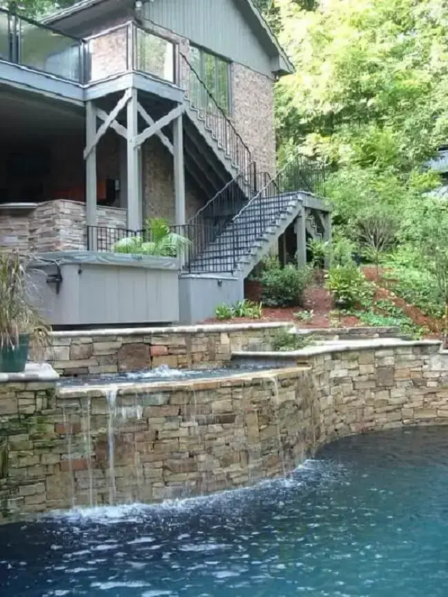 A cascata para piscina de pedra se torna uma extensão da casa