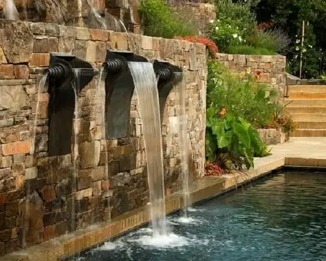 A cascata para piscina de pedra traz um toque rústico para área de lazer. 