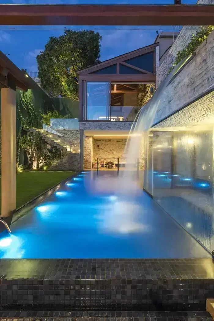 A iluminação noturna traz sofisticação para a cascata de pedra para piscina