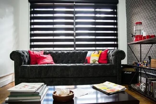 As almofadas coloridas quebram a sobriedade do sofá capitonê preto