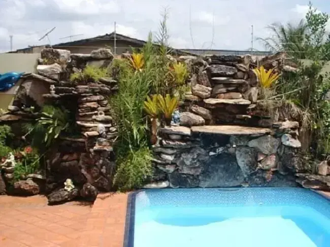 As cascatas de pedras naturais para piscina normalmente são acompanhadas por plantas.