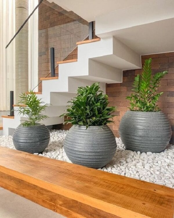Decoração com jardim artifical embaixo da escada e vasos cinza
