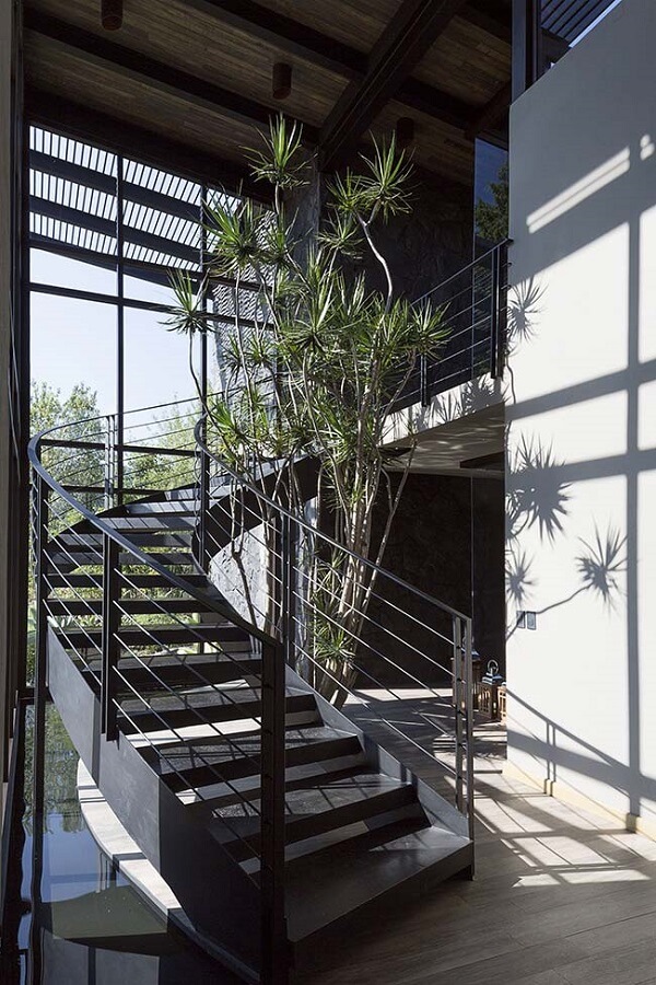 Jardim embaixo da escada curva e moderna preta