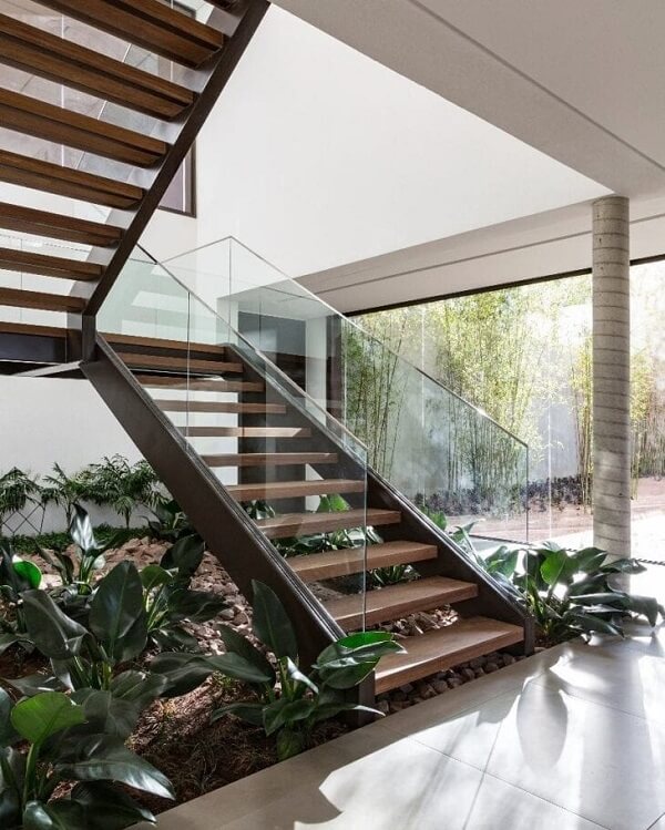 Jardim embaixo da escada na sala de estar rústica com corrimão de vidro