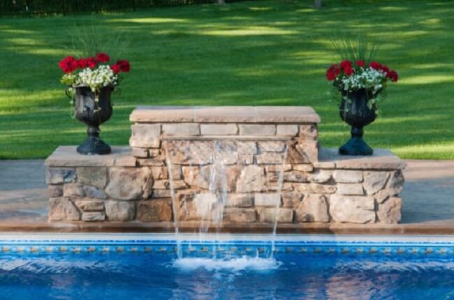 Modelo de cascata para piscina feita de pedra e vasos decorativos