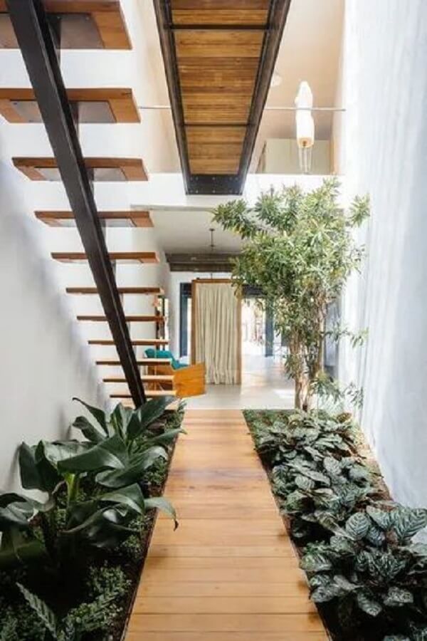 Sala com jardim embaixo da escada de madeira
