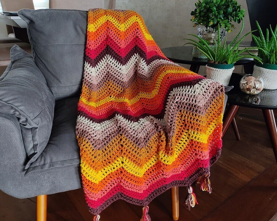 Sala decorada com manta de crochê colorida para poltrona cinza Foto Circulo