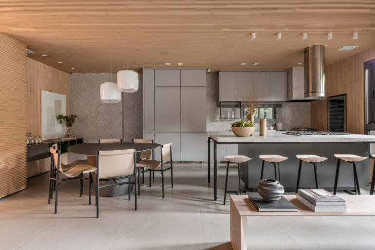 O living e a cozinha ganharam um toque atemporal com muitos elementos em madeira. Projeto de Bohrer Arquitetos