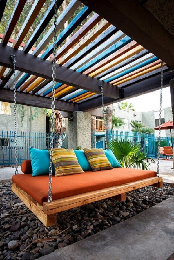 Cobertura para pergolado de ferro e madeira com almofadas coloridas no sofá suspenso