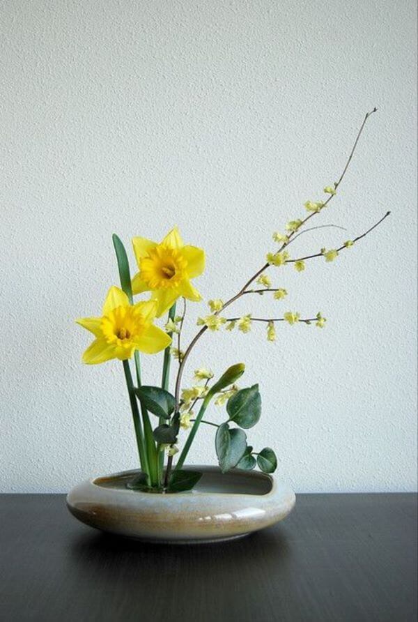 Ikebana com flores amarelas e vaso pequeno 