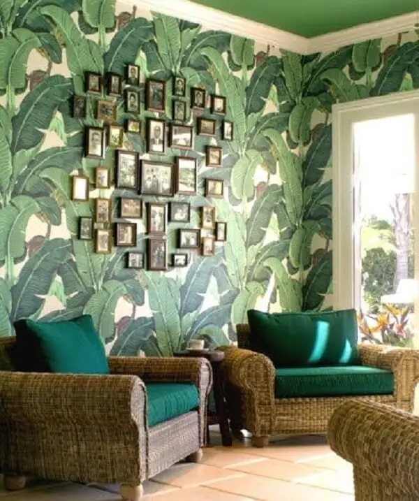 Móveis de vime e papel de parede folhagem decoram a sala de estar. Fonte: Completely Coastal