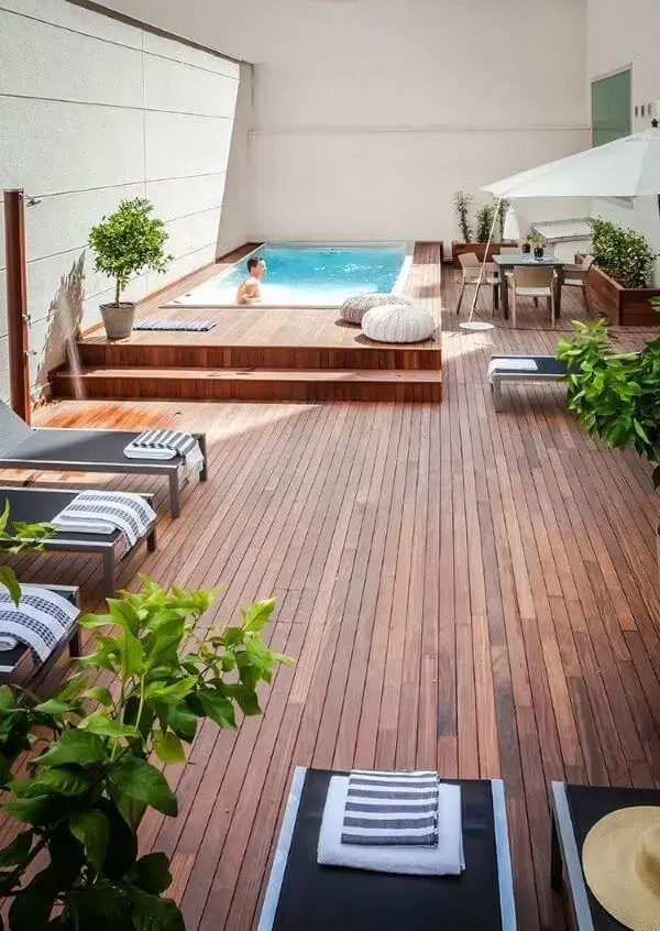 Piscinas modernas com deck de madeira e móveis confortáveis para receber amigos