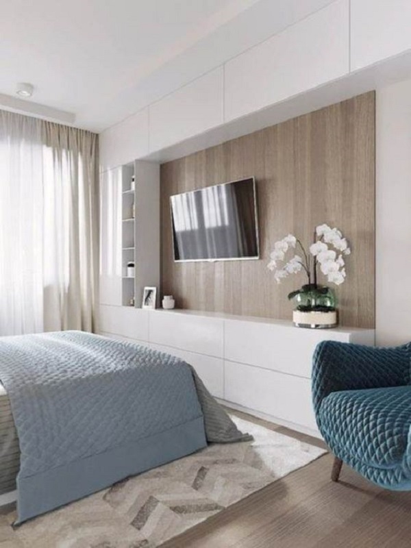Rack minimalista para quarto branco com cama de casal e poltrona azul