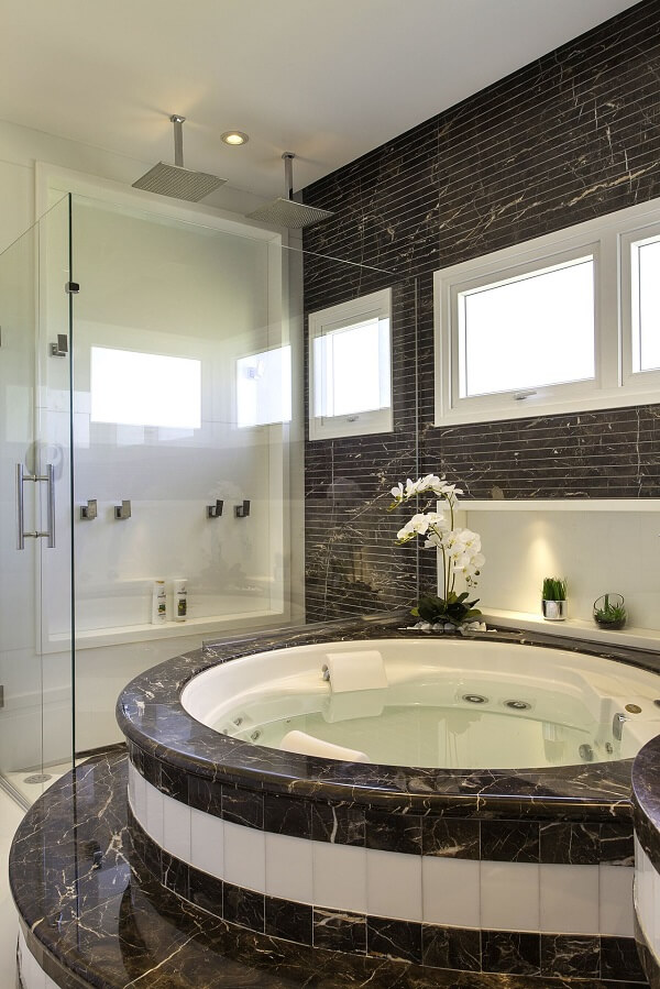 Banheiro chique com banheira redonda e revestimento de mármore preto