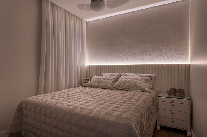 Cortina com tecido branco e cabeceira com LED decoram o quarto. Fonte: Marcia Addor
