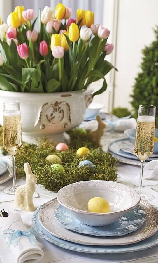 Decoração de mesa para a Páscoa com ovos e flores coloridas e mini coelhos Foto Deavita