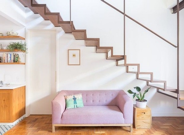 Lavabo embaixo da escada com sofá rosa