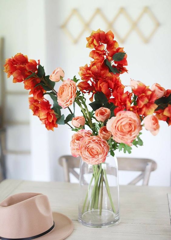 Arranjo de mesa com vaso de vidro e flores coral