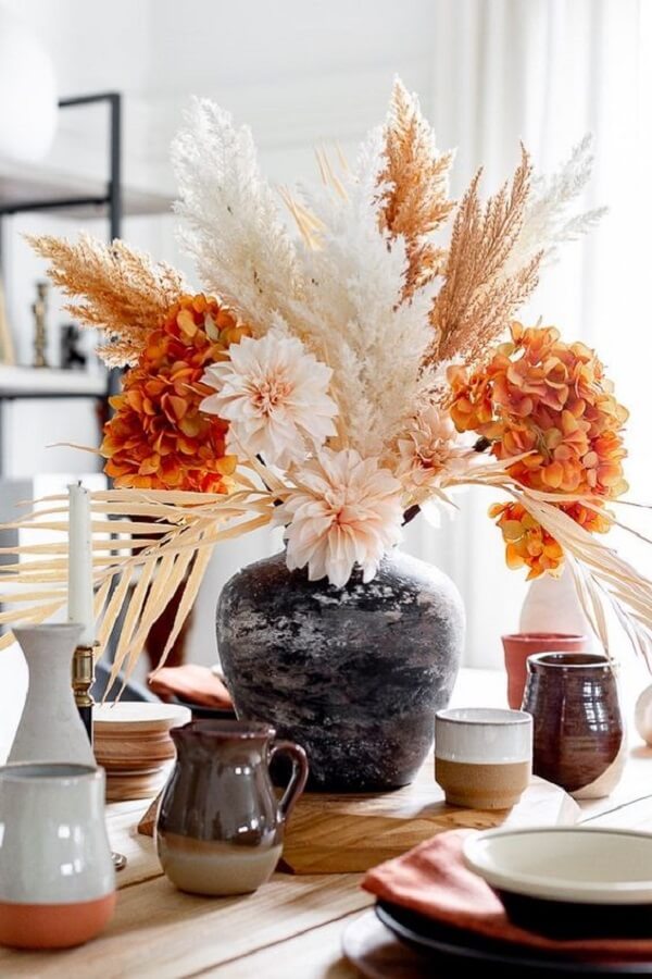Arranjo de mesa com vaso pequeno na cor preta decorado com flores laranja