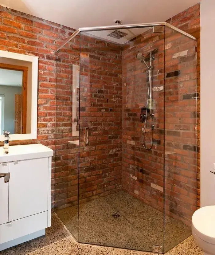 Banheiro com box de vidro e tijolo de demolição. Fonte: NZ Builders