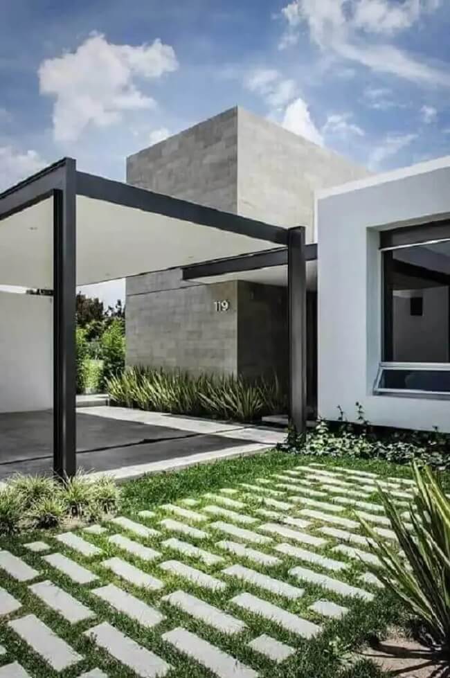 Casa com fachada cinza e garagem lateral com piso concregrama