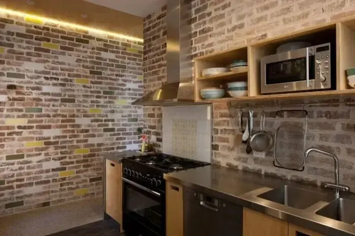 Cozinha funcional com armários de madeira e tijolo de demolição. Fonte: Studio 74