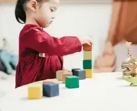 Criança brincando com peças de montar em cantinho de brinquedos Foto Pexels
