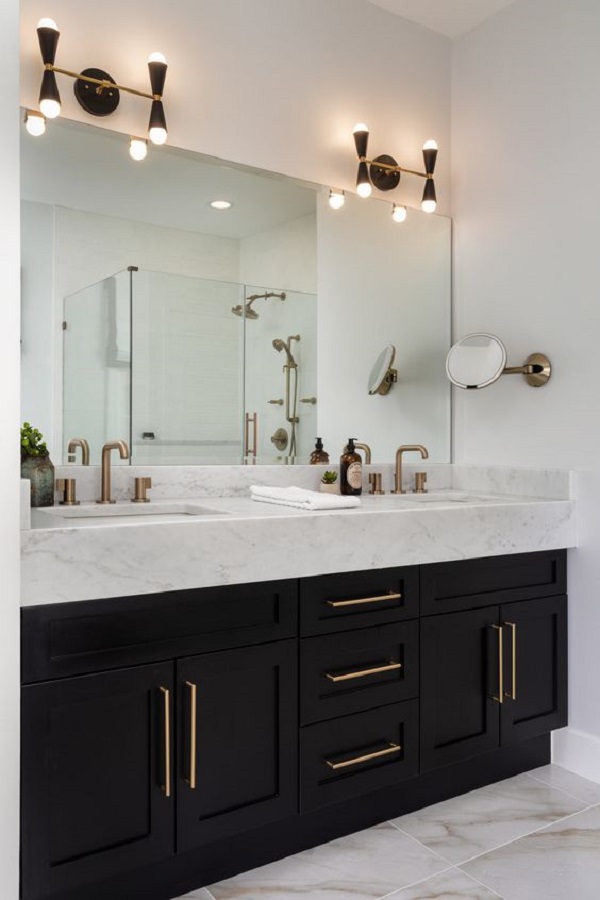 Pia de banheiro de mármore com armários pretos e detalhes em dourado