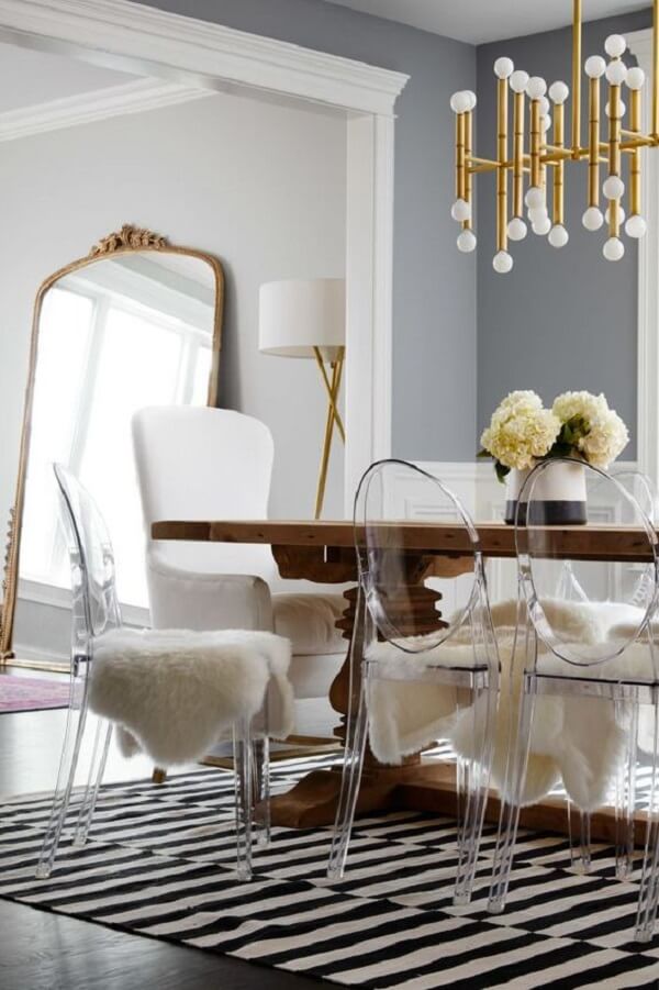 Sala de jantar com cadeira acrilico transparente e tapete listrado