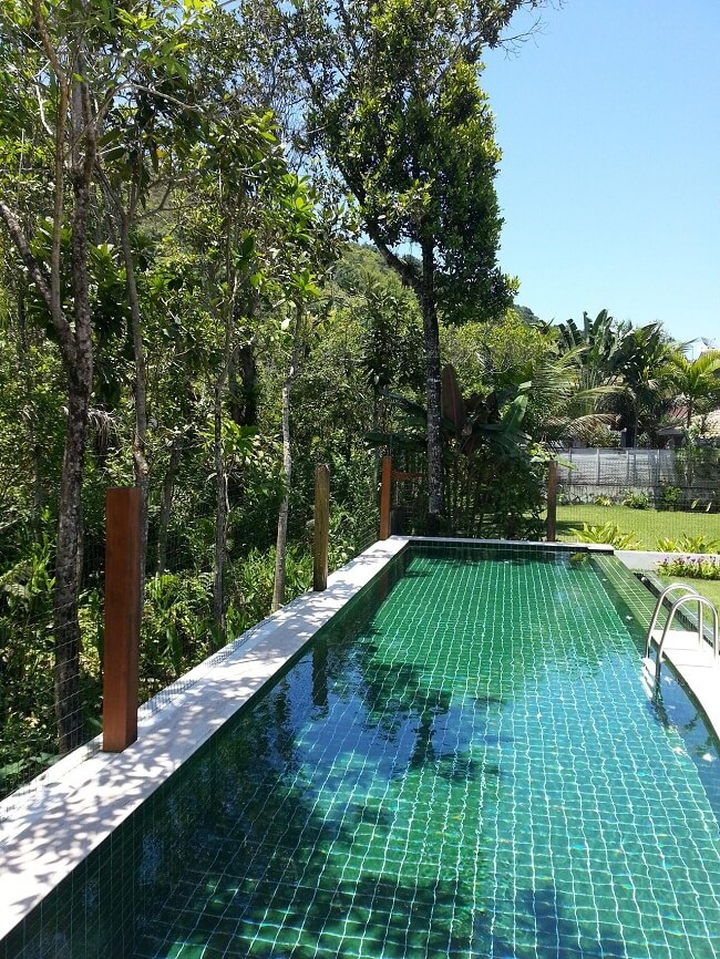 A piscina retangular grande se conecta com o paisagismo do terreno