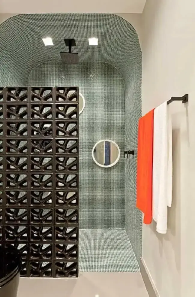 Banheiro moderno com pastilhas de vidro e meia parede de cobogó preta