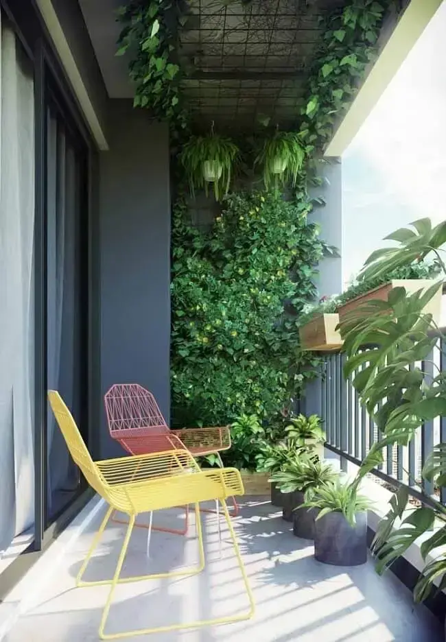 Cadeiras coloridas e parede de plantas decoram a varanda