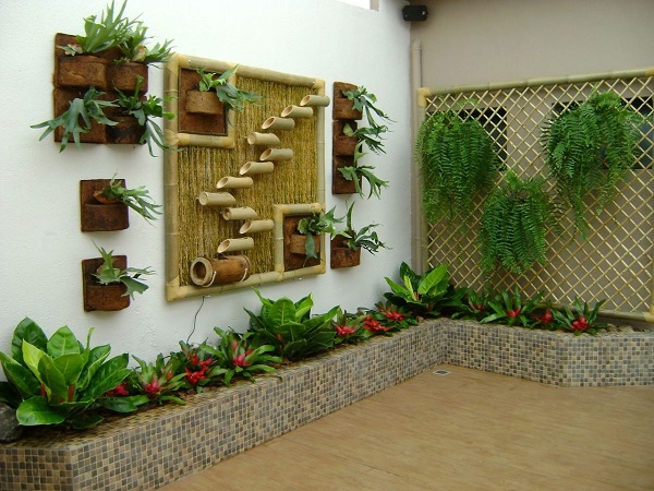 Jardim rústico no quintal com canteiro de plantas e floreira de bambu na parede