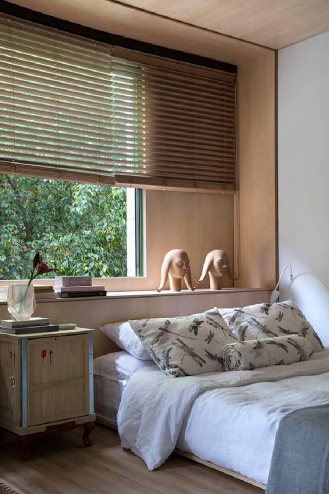 Persiana de madeira barram a entrada de luz natural a cama embaixo da janela