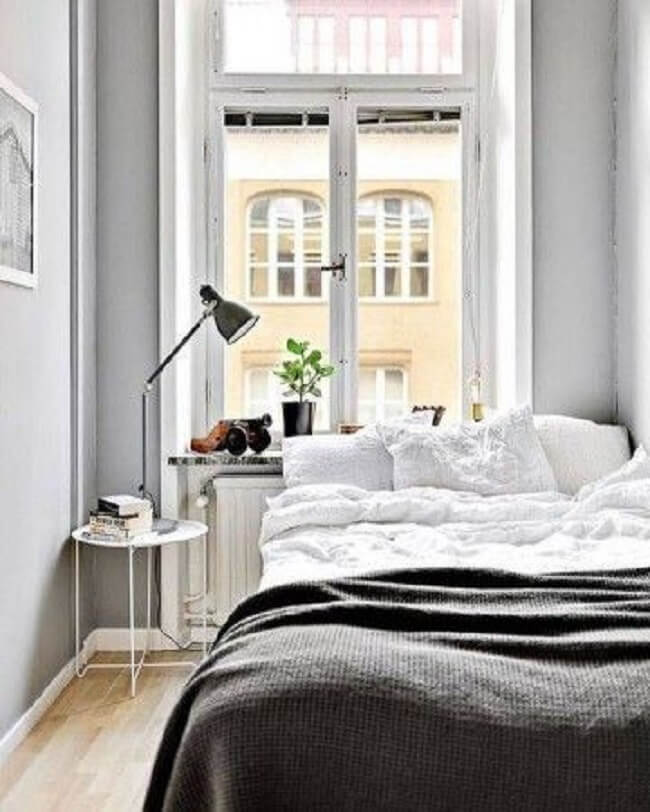 Quarto clean e minimalista com cama embaixo da janela