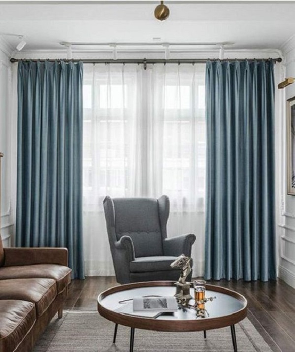 Sala de estar com cortina azul clara e sofá de couro marrom