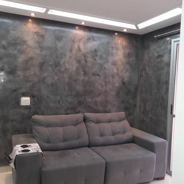 Sala de estar com marmorato na parede e sofá cinza